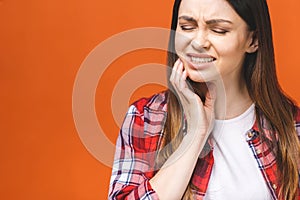 Young beautiful woman isolated on orange background suffering from severe toothache, feeling pain so strong that she is pressing