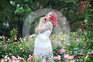 Young beautiful woman ist standing in the garden of pink roses w