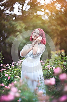 Young beautiful woman ist standing in the garden of pink roses w