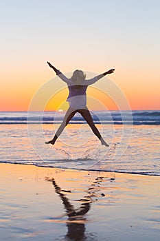 Young beautiful woman jumping in the beach.