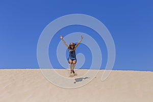 Young beautiful woman jumping on the dunes in Portugal. Summertime, fun and holidays concept