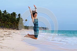 Young beautiful woman jumping on a tropical beach