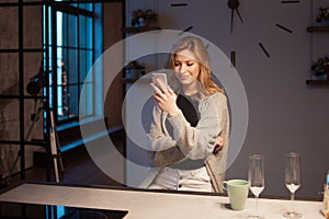 Young beautiful woman in the kitchen with smartphone. Looking for online cooking recipe.