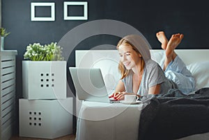 Young beautiful woman with laptop and cup of coffee in morni