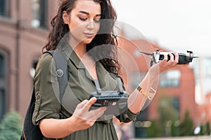 Young beautiful woman launching drone quadcopter at urban background. cityscape. modern device
