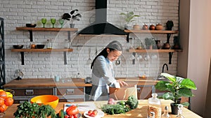 Young Beautiful Woman lays out the products from the package on the table. A beautiful young woman in a good mood is