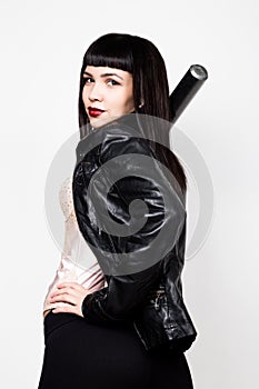 Young beautiful woman in a leather jacket, posing with baseball bat.