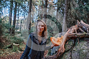 Young beautiful woman in leather jacket with pumpkin in a forest