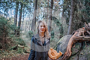 Young beautiful woman in leather jacket with pumpkin in a forest