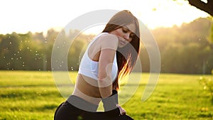 Young beautiful woman listening music at park while running. Portrait of smiling sporty girl with earphone looking at