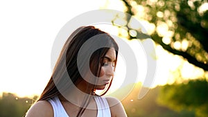 Young beautiful woman listening music at park while running. Portrait of smiling sporty girl with earphone looking at