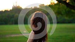 Young beautiful woman listening music at park while running. Portrait of smiling sporty girl with earphone looking at