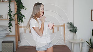 Young beautiful woman listening to music and dancing at home in morning