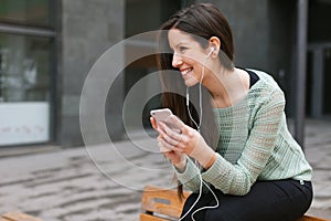 Young beautiful woman listening to music with phone in outdoors.
