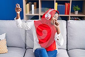 Young beautiful woman listening to music singing song at home