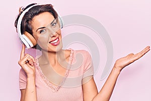 Young beautiful woman listening to music using headphones celebrating achievement with happy smile and winner expression with