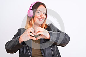 Young beautiful woman listening to music using headphones over isolated white background smiling in love showing heart symbol and