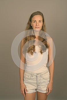 Young beautiful woman with long blond hair against gray background