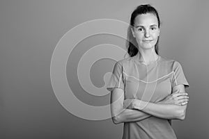 Young beautiful woman with long blond hair ready for gym against gray background