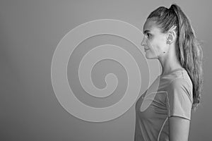 Young beautiful woman with long blond hair ready for gym against gray background