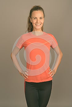 Young beautiful woman with long blond hair ready for gym against gray background