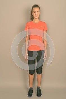 Young beautiful woman with long blond hair ready for gym against gray background