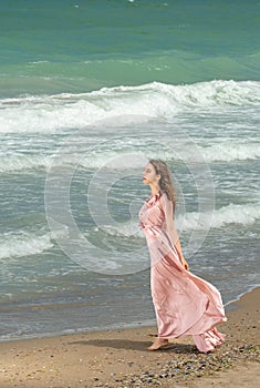 Young beautiful woman with long dress ,romantic mood on the beach with waves, Black sea side  Bulgaria