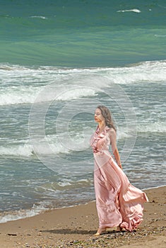 Young beautiful woman with long dress ,romantic mood on the beach with waves, Black sea side  Bulgaria