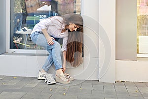 Young beautiful woman with long hair bent over to change her leg into different shoes