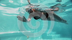 The young beautiful woman with long hair swim in the pool under water