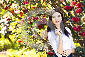 Young beautiful woman with long straight dark hair posing in spring garden