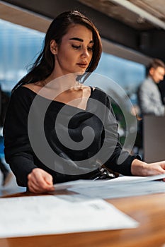 Young beautiful woman looking at menu deciding what to order in modern cafe.