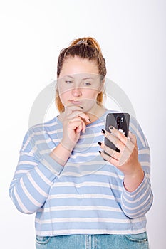 Young, beautiful woman looks thoughtfully at a smartphone