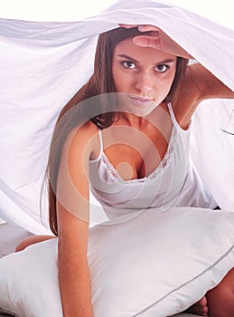 Young beautiful woman lying in bed under cover