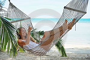 Young beautiful woman lying in a hammock with laptop.