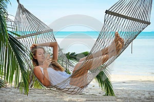 Young beautiful woman lying in a hammock with phone.