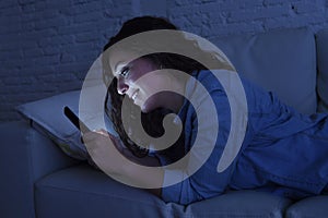 Young beautiful woman lying on home couch using mobile phone internet addiction concept