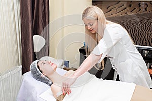 Young beautiful woman lying at the table in beauty salon. Professional beautician applying cosmetic treatment and procedure. Spa,