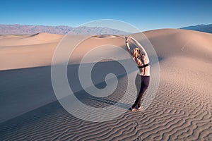 Young beautiful woman makes yoga fitness exercise on the sand mountain at sunset. Health lifestyle concept. Woman meditating