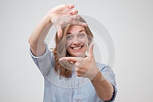 Young beautiful woman making frame with her hands smiling over white background. P