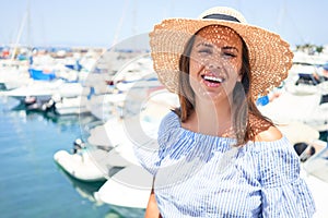 Young beautiful woman at marine port around boats, smiling happy with seaport at the background