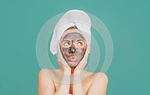 Young beautiful woman in a mask for the face of the therapeutic black clay. Spa treatment. Cosmetic mud facial procedure