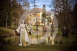 Young beautiful woman in medieval dress with a romantic mood in the park ,tree swing