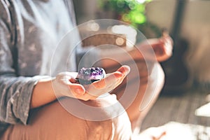 Young beautiful woman is meditating with a crystal in her hand.