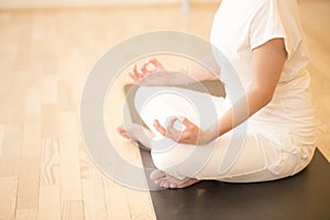 Young beautiful woman meditating in lotus pose sitting on the fl