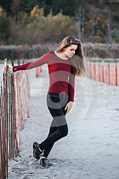 Young beautiful woman with messy long hair on windy day outdoor on the shore beach