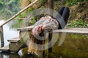 Young beautiful woman model with long blond hair sitting with different emotions laughter, sadness, sorrow, thoughtfulness on a wo