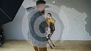 Young beautiful woman model posing for photographer while he is shooting with a digital camera in photo studio indoors