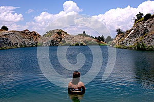 Young, beautiful woman model standing in a lake of a old sandmining place on holiday in Spain