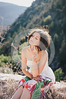 Young beautiful woman in a modern dress with mehendi posing among mountains